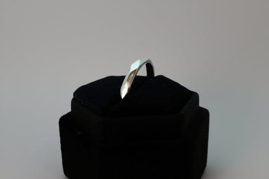 Silver ring on a black cushion against a white background