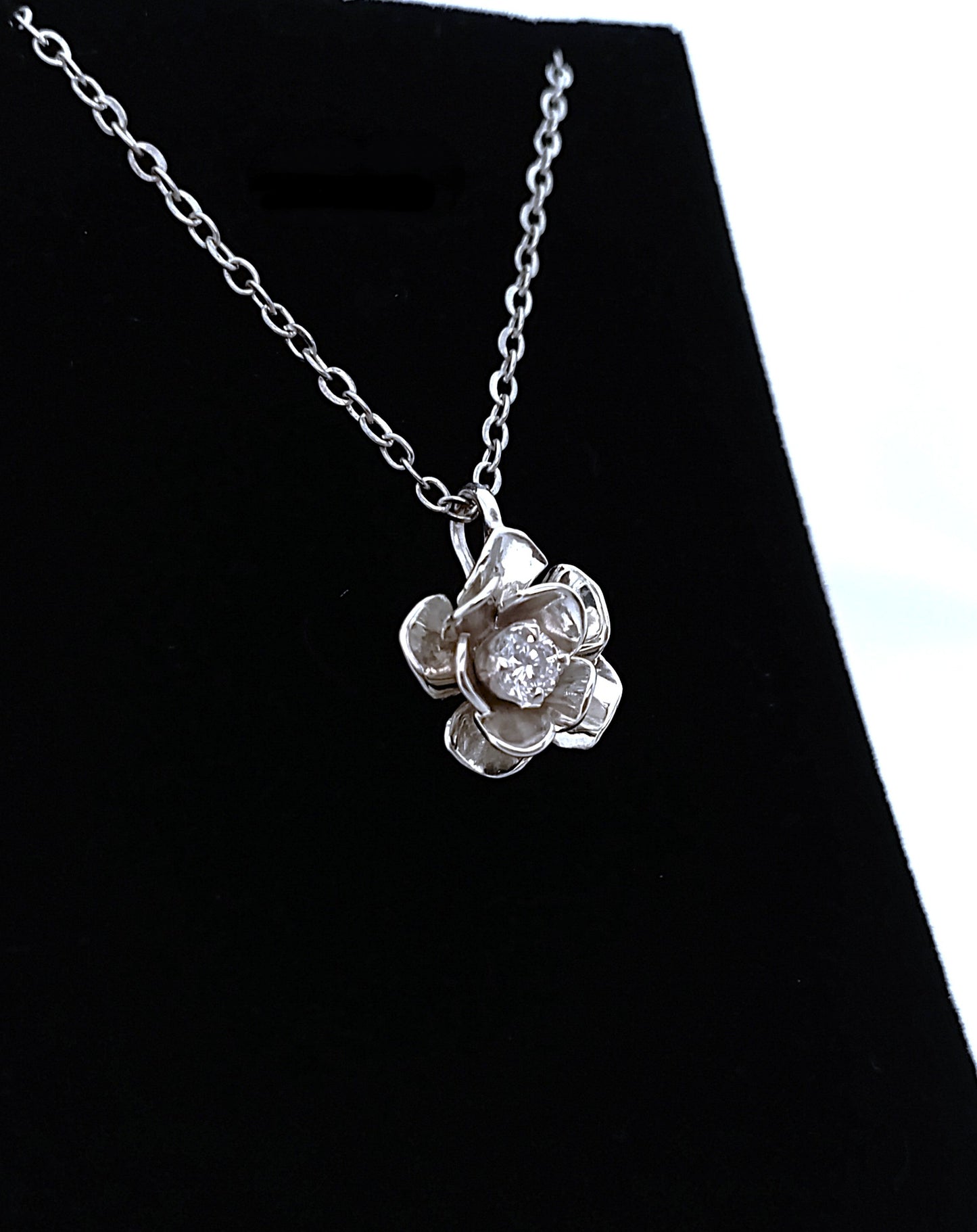 Silver necklace with a flower-shaped pendant on a black background