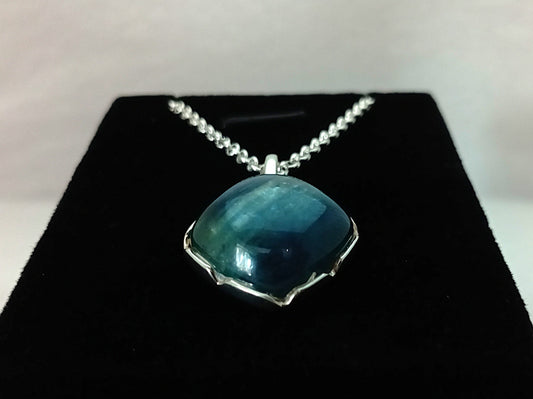 Blue pendant necklace on a black stand with a white background