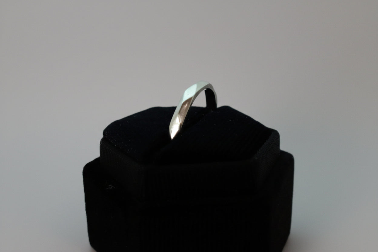 Silver ring on a black cushion against a white background